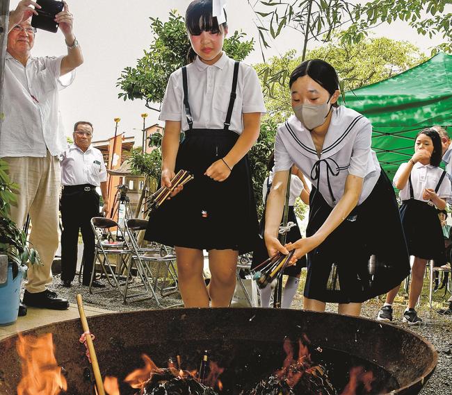 炎の中に使い古した筆をくべる参加者＝浜田市蛭子町、神並山天満宮