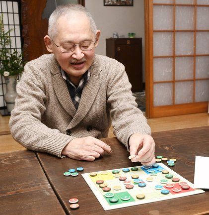 ボードゲーム「Ｍａｎｐｏ’ｓ４色碁石」を実演してルールを説明する発案者の太田満保さん＝出雲市平田町