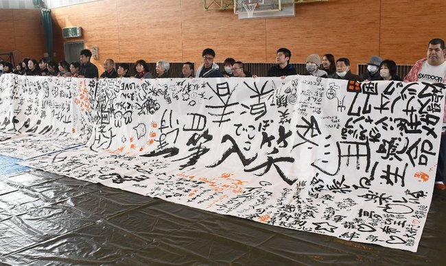 夢や目標、好きな言葉を書いた「寄せ書き」を広げる参加者=14日、米子市皆生3丁目の米子サン・アビリティーズ