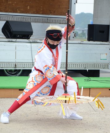 傘を下に向け、すくうような動きで踊る小西利雄さん＝安来市中海町、道の駅あらエッサ