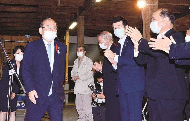 報告会場に入り、支持者から拍手を受ける久保田章市氏（左）＝１７日午後１０時１８分、浜田市黒川町、事務所