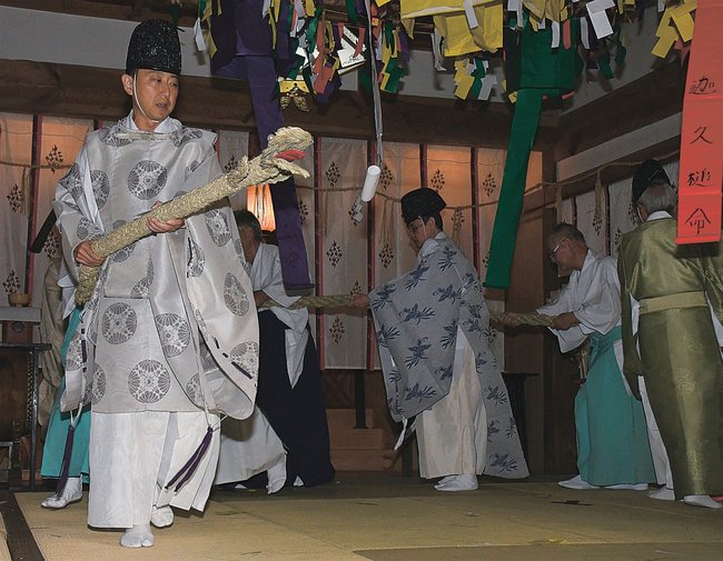 わらのヘビを手に地域の安寧を祈願する神職ら＝島根県邑南町日貫、大原神社