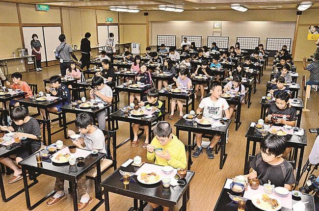 新型コロナ対策で離れて座り、黙々と夕食を食べる児童＝米子市皆生温泉３丁目、三井別館