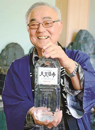 販売開始する温泉水入りペットボトルを手にする横田雪生組合長＝浜田市金城町追原、かめや旅館