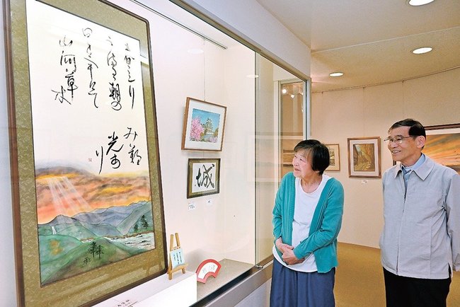 合作「春賛歌」を眺める水野博司さんと妻の清槙さん＝出雲市西平田町、ぎゃらりーＨａｎｄ＆Ｈａｎｄ