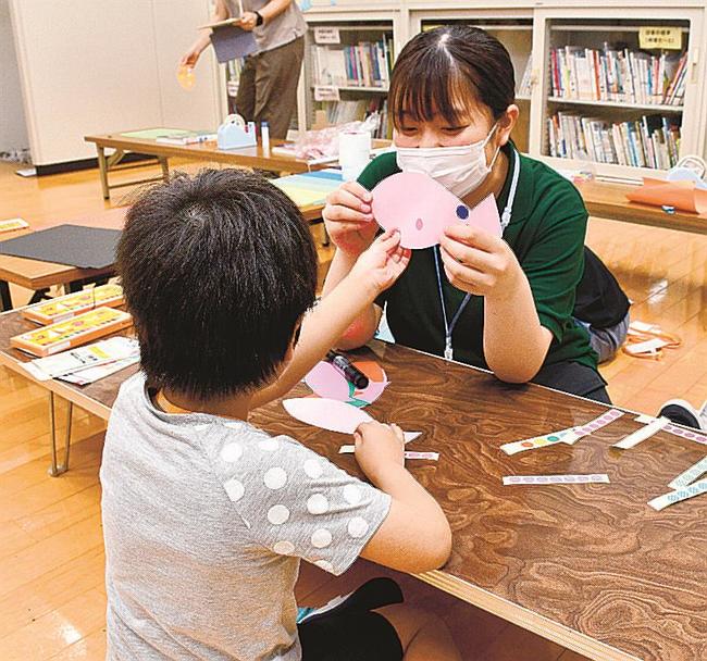 学生（右）にサポートしてもらい、シールを貼る参加者＝松江市浜乃木７丁目、島根県立大