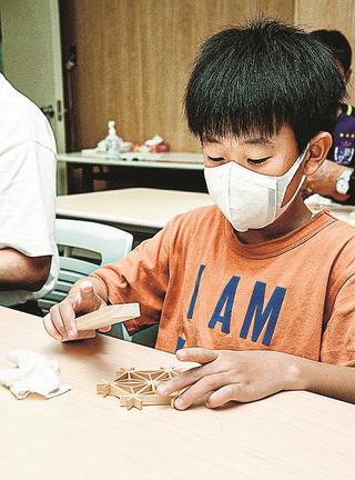 組子細工のコースターを制作する子ども＝益田市内田町、萩・石見空港