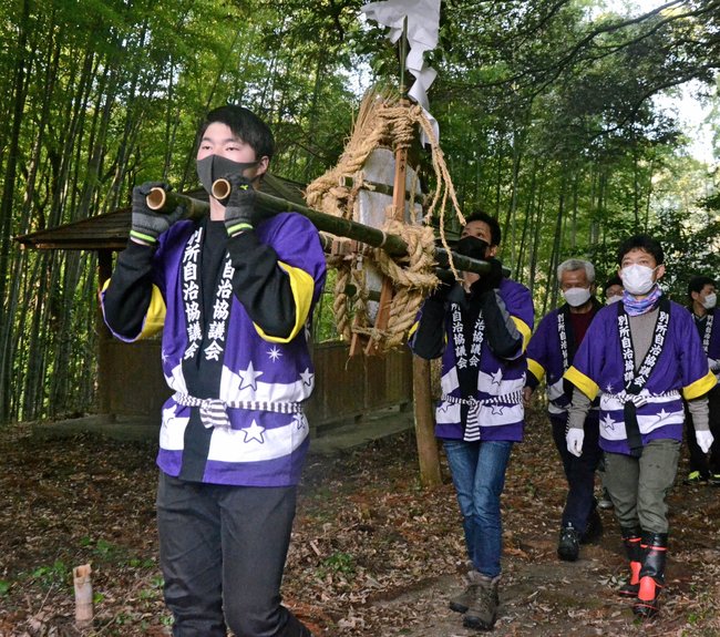 大餅を担いで険しい山道を登る地元住民＝松江市八雲町東岩坂、星上山