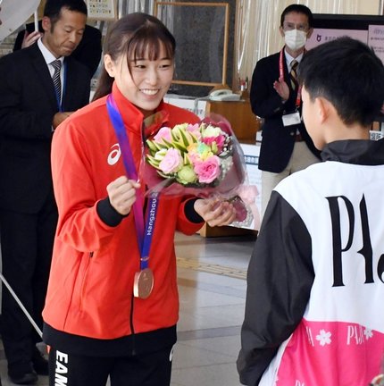 花束を受け取り、ガッツポーズで応える三上紗也可選手＝鳥取市東町１丁目、鳥取県庁