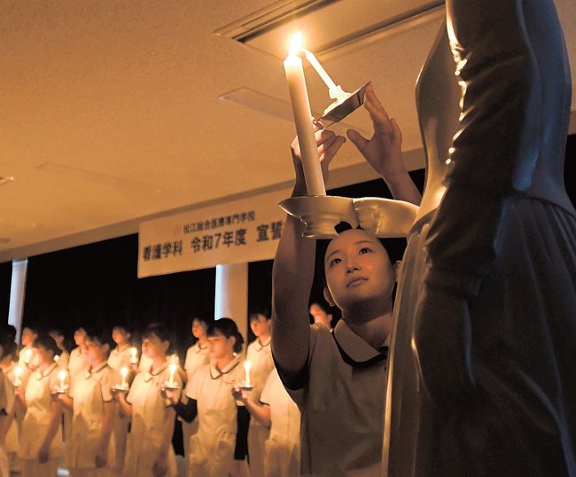 決意に満ちた表情でナイチンゲール像から火を受ける学生＝松江市上大野町、松江総合医療専門学校