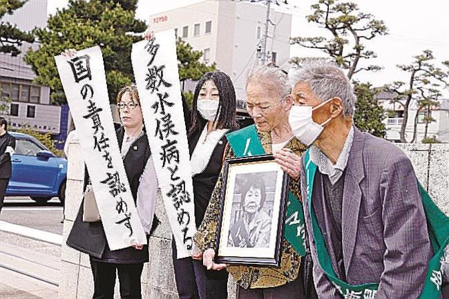 新潟水俣病訴訟の判決後、新潟地裁前で「国の責任を認めず」などと書かれた垂れ幕を掲げる弁護士ら＝１８日