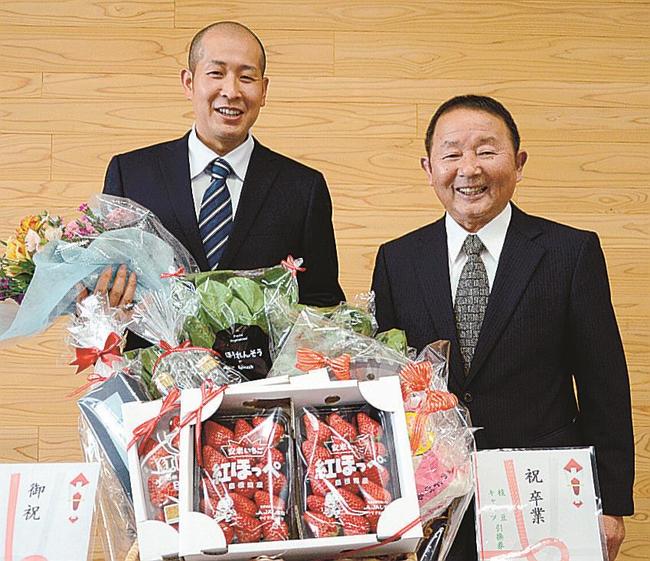 門出を祝う記念品を前に笑顔を見せる佐小田健さん（左）と山本耕一代表理事＝安来市安来町、市役所