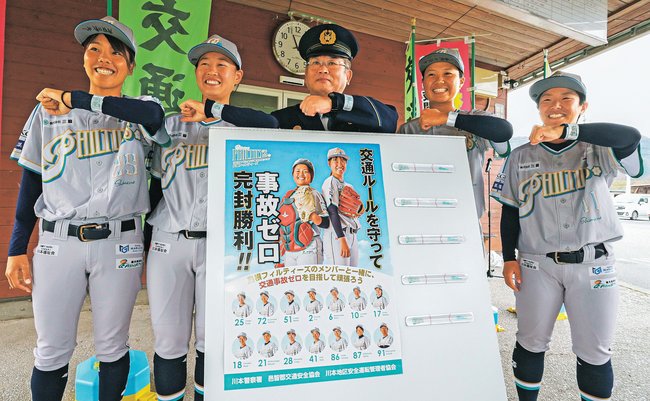 ポスターと反射バンドを披露する島根フィルティーズの選手と岩垣善保署長(中央)=島根県川本町因原、道の駅インフォメーションセンターかわもと