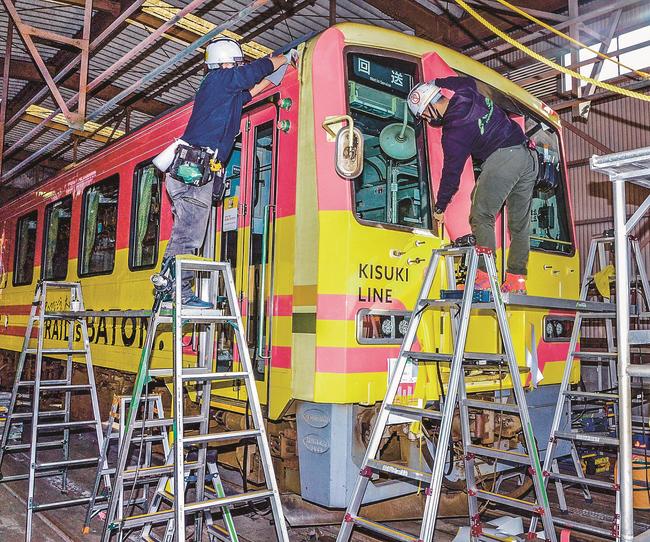 車体にラッピングフィルムを貼る作業員＝出雲市東神西町、後藤総合車両所出雲支所