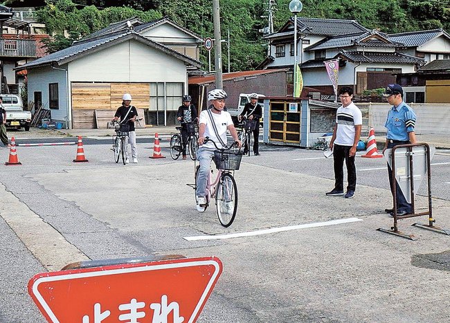 自転車に乗って一時停止をするインドネシア人の技能実習生＝島根県西ノ島町浦郷