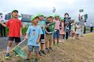 そばを植えた神戸川の土手で「瑞風」を歓迎する園児＝出雲市古志町
