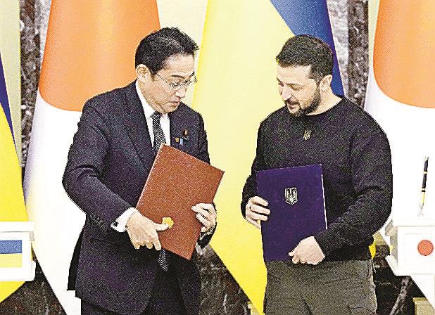 記者会見の冒頭、署名文書を交換する岸田首相（左）とウクライナのゼレンスキー大統領＝２１日、キーウ（共同）