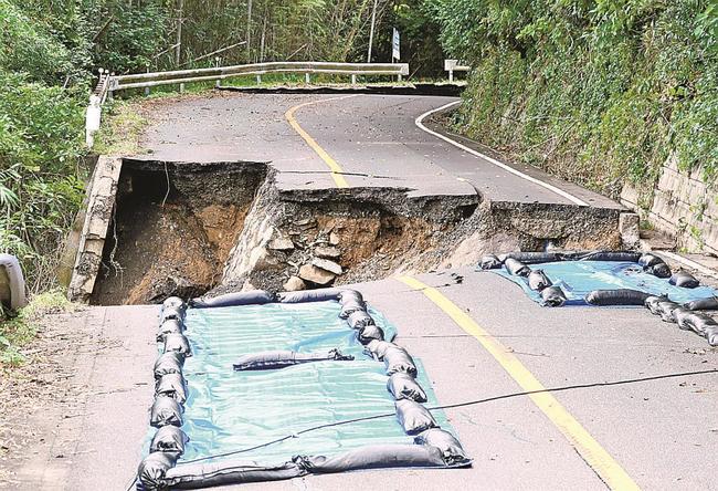 県道の崩落現場。下部に二つの石積み擁壁が確認できる。県道の右側がブロック擁壁＝１１日午後、出雲市大社町日御碕