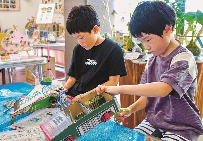 真剣な表情で工作に取り組む児童＝松江市玉湯町玉造、出雲玉作資料館