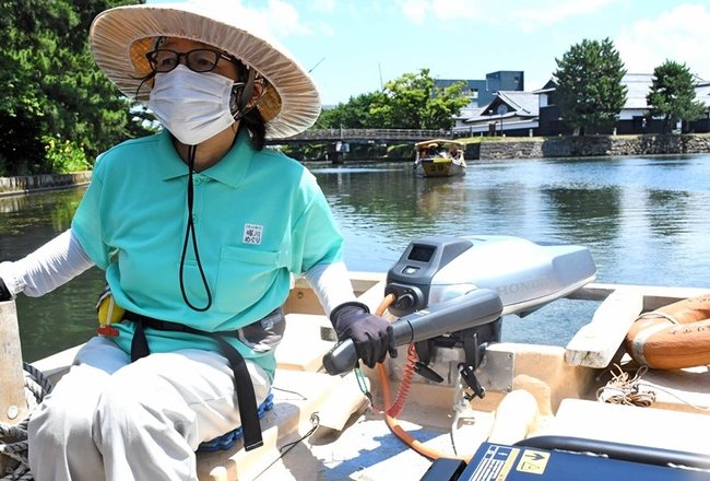 試作型の小型電動推進機を搭載した遊覧船を操縦する船頭＝松江市北堀町