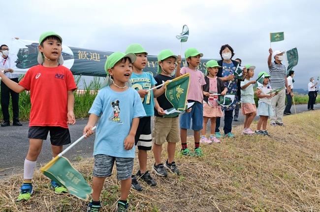そばを植えた神戸川の土手で「瑞風」を歓迎する園児＝出雲市古志町