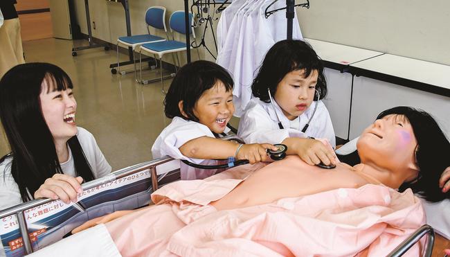 人形に聴診器を当て、心音を聞く子どもたち＝出雲市西林木町、島根県立大出雲キャンパス