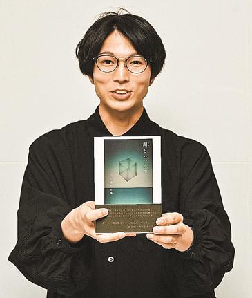 著書を手に笑顔を見せる田村穂隆さん＝松江市内
