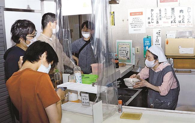 常連客にうどんを出す山室晴美さん（右）＝島根県津和野町後田、くぼたうどん店