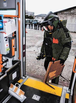 防爆服を着てバスの爆発物に対応する機動隊員＝大田市大田町、石見交通大田営業所