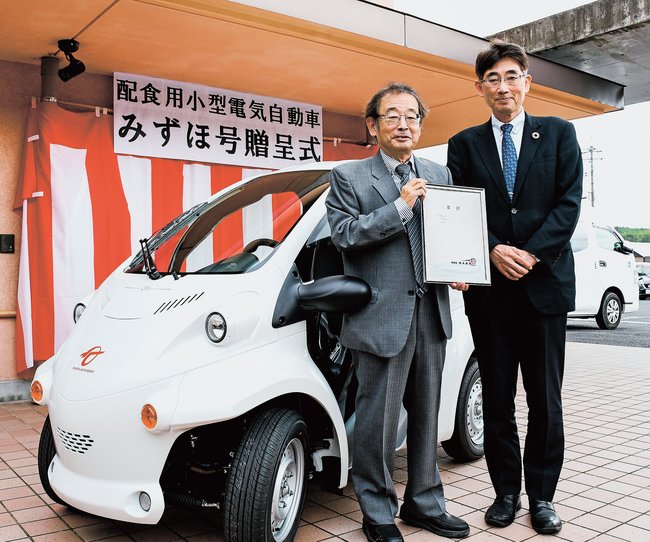 配食用小型電気自動車の寄贈を受けたひらた福祉会の川瀬英理事長（左）。右は財団の安徳和典福祉事業部長＝出雲市東郷町、エルパティオ三葉園