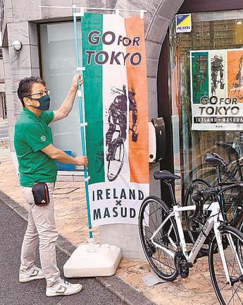 アイルランド事前合宿を歓迎する旗（五輪、パラリンピック共通）を出す自転車販売店員＝益田市駅前町