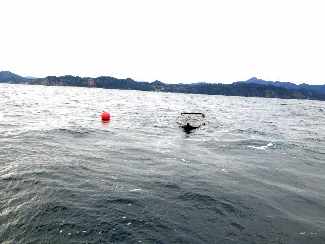 木造船と設置されたブイ＝８日午後２時４０分、島根県隠岐の島町犬来沖南東３・５キロの海上（隠岐海上保安署提供）