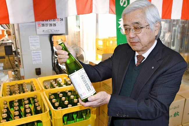 絞りたての新酒を手に取る米田則雄社長＝松江市南田町、米田酒造