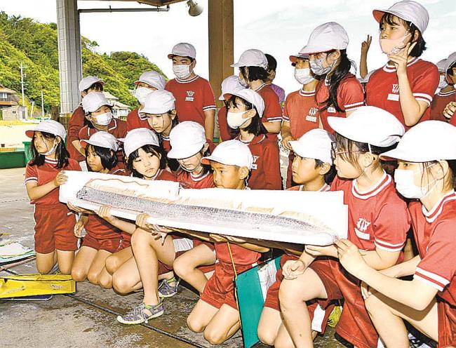 深海魚・リュウグウノツカイと記念撮影する安田小学校の児童＝益田市飯浦町、飯浦漁港