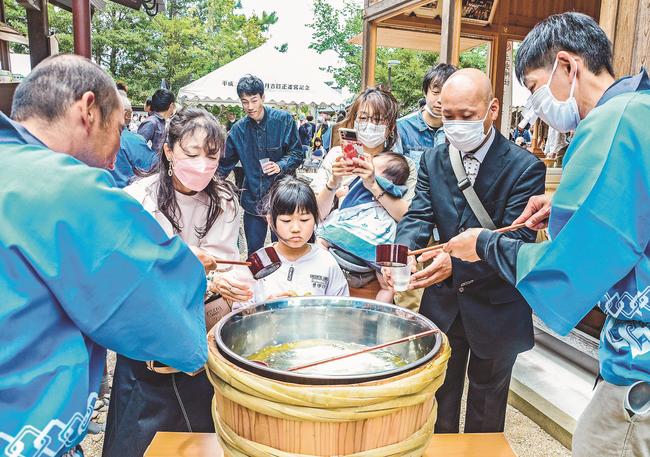 新酒の振る舞いを受ける来場者＝出雲市斐川町併川、万九千神社
