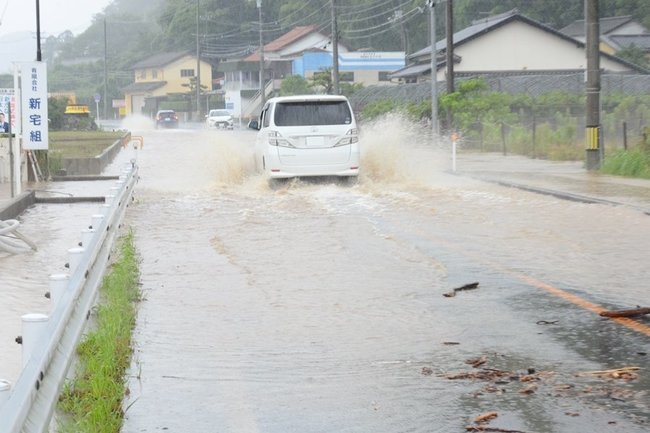 冠水した国道431号で、水しぶきを上げながら走る車＝８日午前９時52分、出雲市大社町菱根