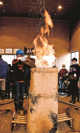 粘土で作った炉に木炭を入れる児童＝島根県奥出雲町大呂、古代たたら体験学習工房