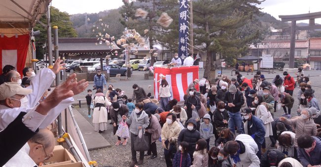 福豆や菓子を受け止める参拝者＝大田市川合町、物部神社