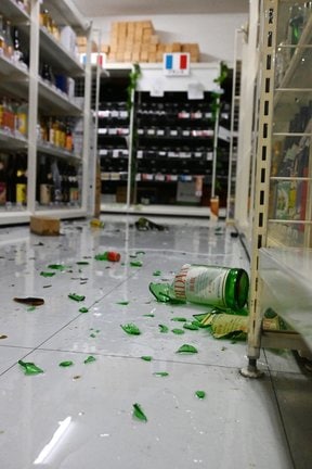 棚から落ちて破片が散らばった酒類の瓶=6日午前10時45分、松江市学園1丁目、酒ゴリラ松江学園店