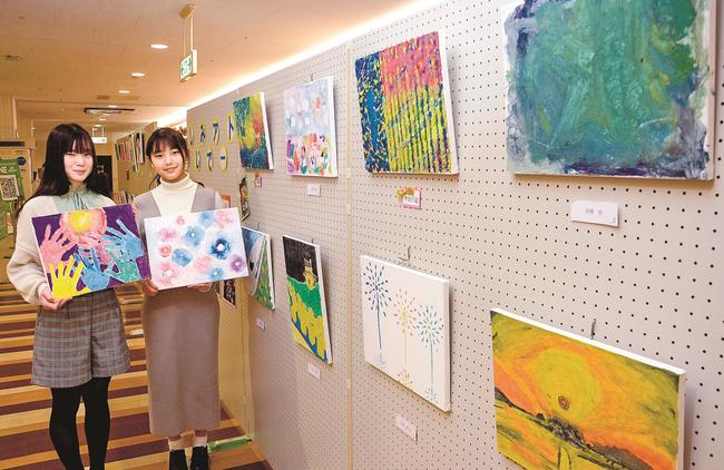 シジミ殻の絵の具作品を手にする松林瑠那さん（左）と伊達妃陽さん＝松江市東朝日町、イオン松江ショッピングセンター