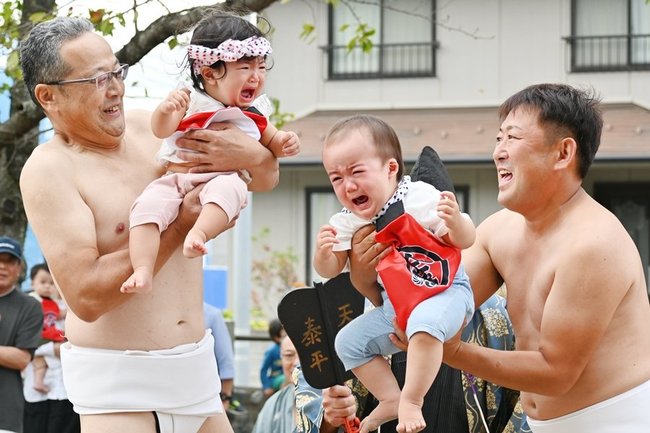 氏子に抱きかかえられ泣き声を上げる乳児＝米子市淀江町西原、日吉神社