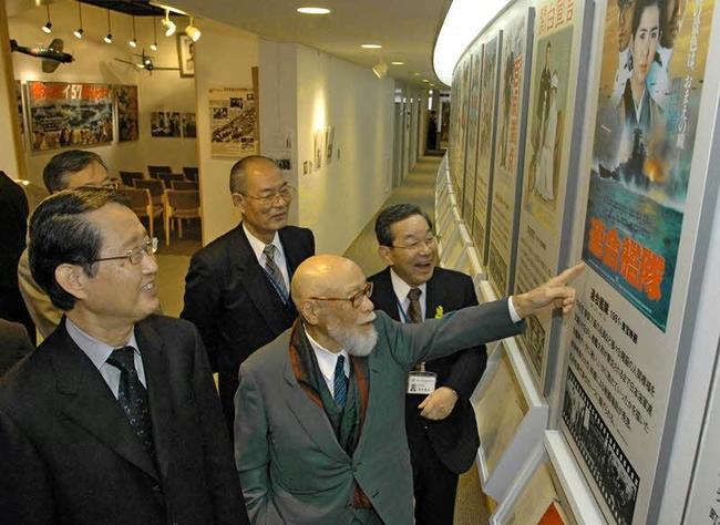 古里の桜江町にオープンした自らの映画記念館で、「連合艦隊」のポスターを指さす松林宗恵監督（右手前）＝２００５年４月