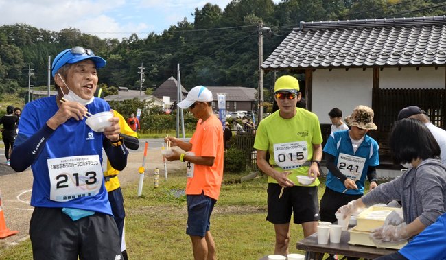 エイドステーションで手打ちそばを頬張る参加者=島根県奥出雲町下横田