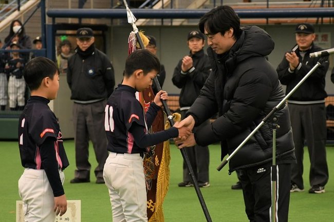 優勝した木次野球スポーツ少年団の選手に優勝旗を渡し握手をする和田毅投手（右）＝出雲市矢野町、出雲ドーム
