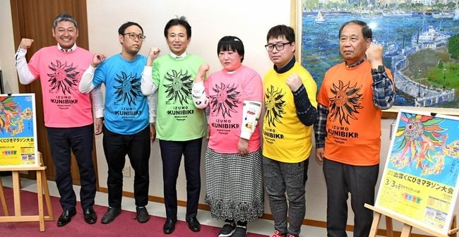飯塚俊之市長(左から3人目)と完成したTシャツとポスターを披露する関係者=出雲市今市町、出雲市役所