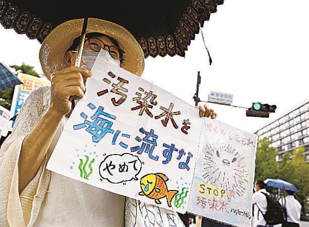 東京電力福島第１原発の処理水海洋放出を巡る政府方針の決定に対し、首相官邸前の抗議集会でメッセージを掲げる参加者＝２２日午前