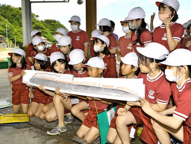 深海魚・リュウグウノツカイと記念撮影する安田小学校の児童＝益田市飯浦町、飯浦漁港