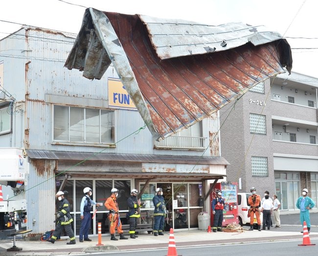 吹き飛ばされたトタン屋根の撤去作業に当たる消防隊員ら＝６日午前１０時２３分、松江市浜乃木４丁目