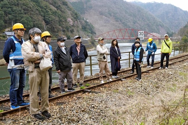 旧JR三江線の線路上でガイドの説明に耳を傾ける参加者=島根県邑南町上田