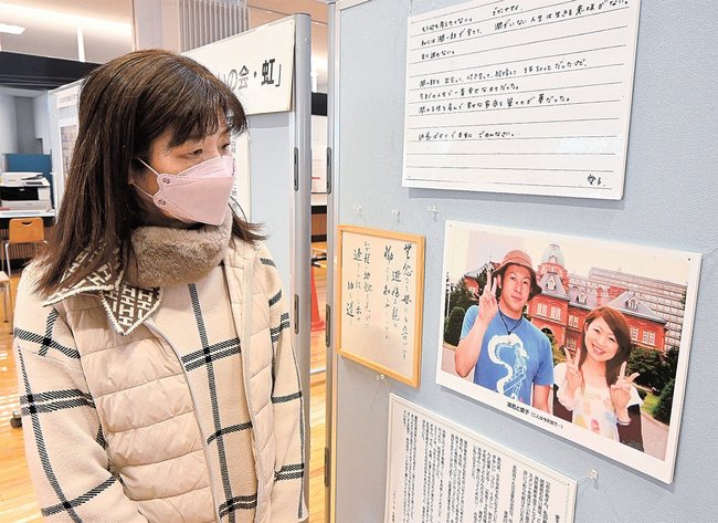 娘と娘婿の写真を見詰める遺族の女性＝雲南市木次町里方、雲南市役所